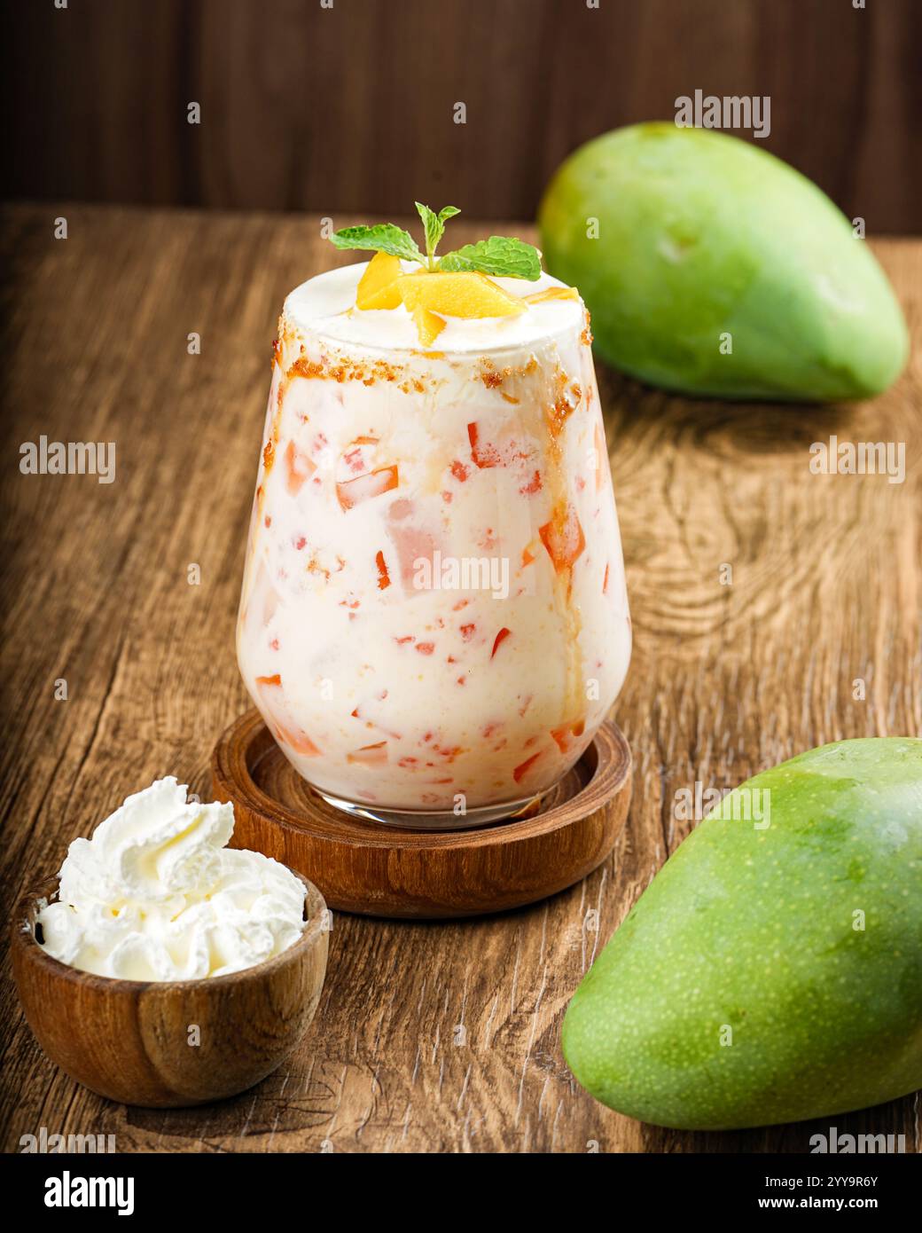 Una ricca e cremosa bevanda galleggiante di mango traboccante di pezzi di mango freschi e ricoperta di panna montata e di graham schiacciati. Ricoperto di fette di mango e. Foto Stock
