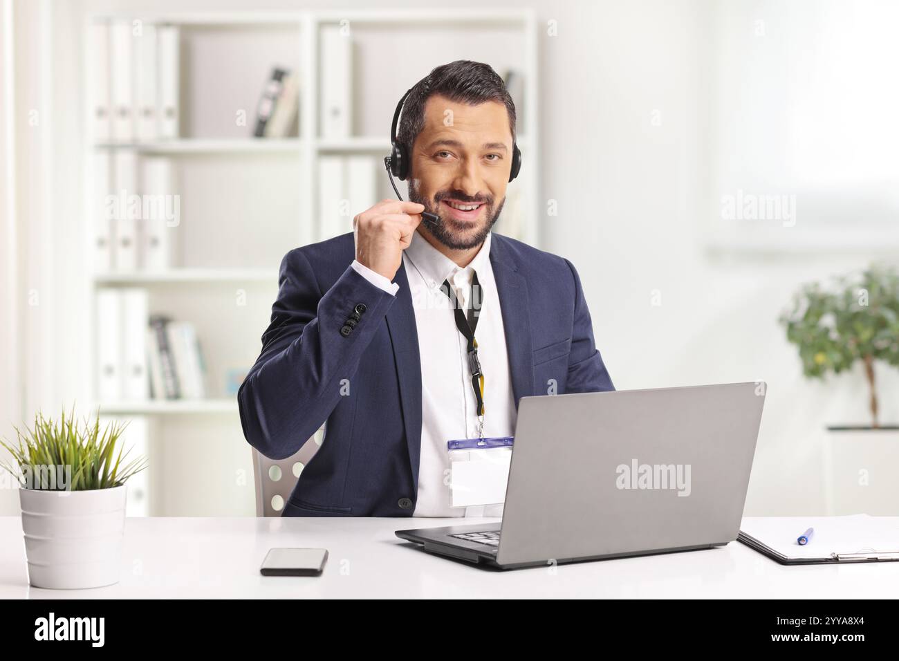 Uomo con una cuffia che lavora su un computer portatile in ufficio Foto Stock