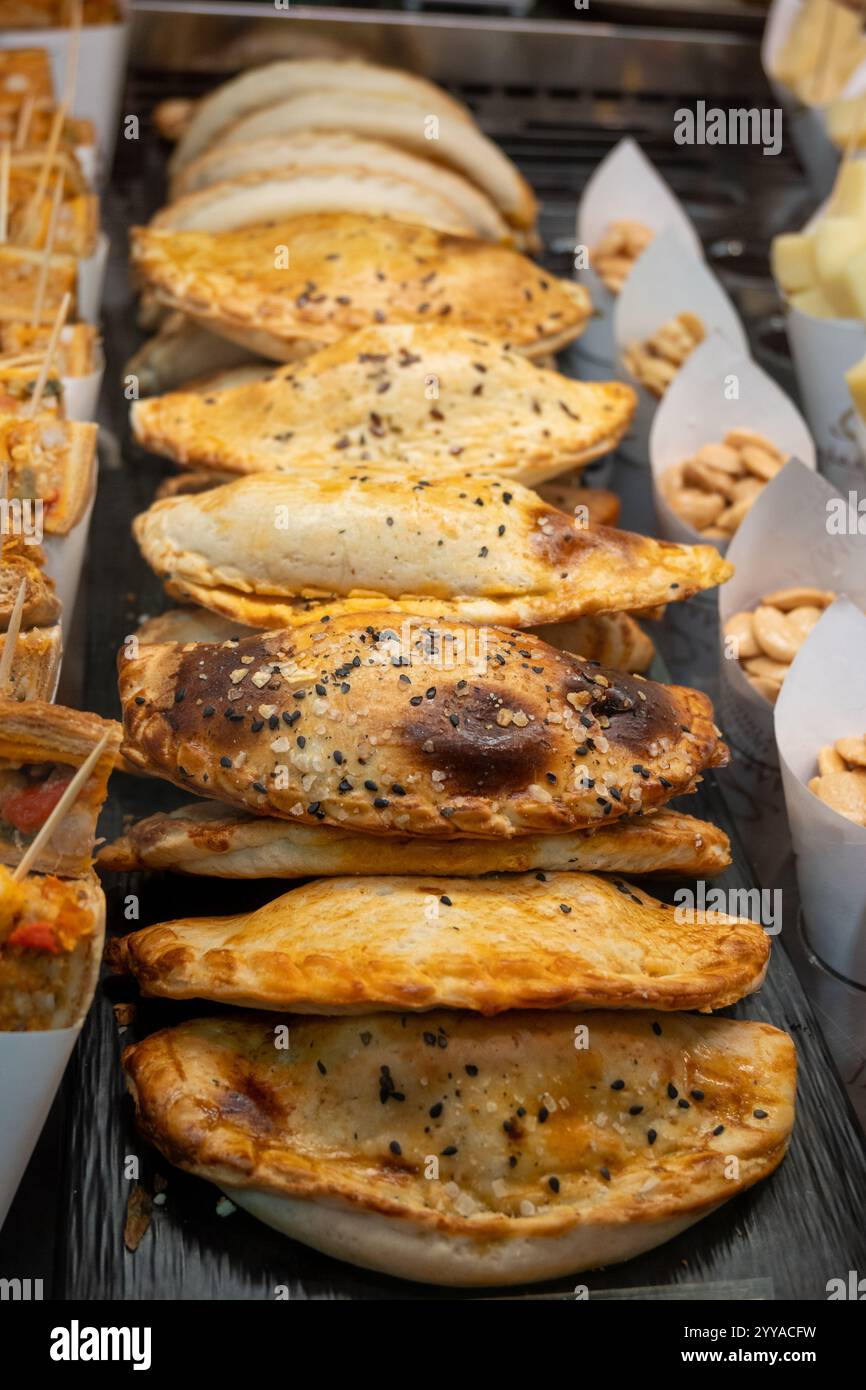 Torte tradizionali spagnole e latinoamericane empanadas con ripieni diversi, al mercato agricolo in panetteria con tonno, cipolla dolce, formaggio di capra Foto Stock