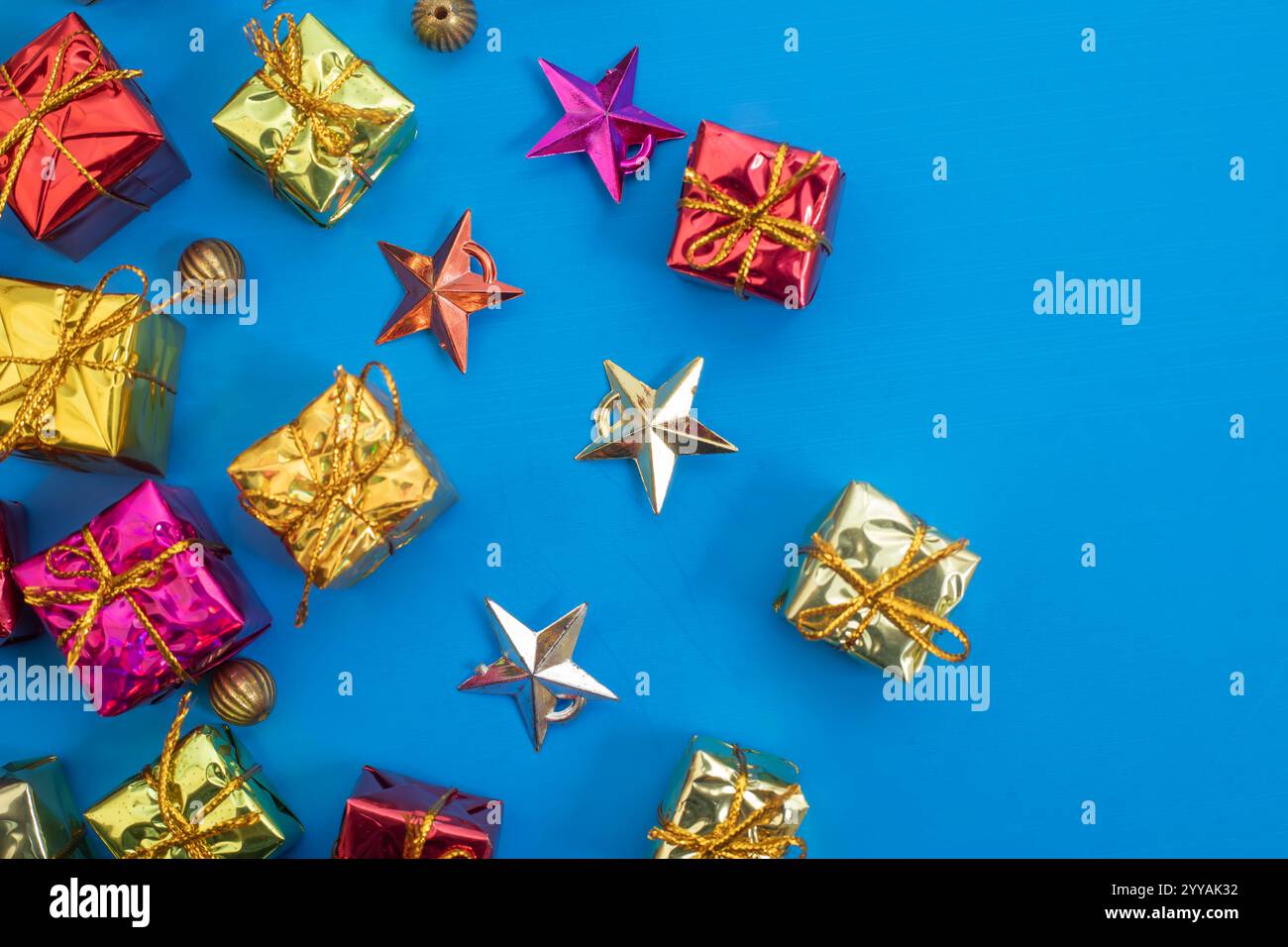 Scatole regalo colorate e stelle ornamentali disposte su uno sfondo blu brillante, perfette per le festività e i biglietti d'auguri. Foto Stock