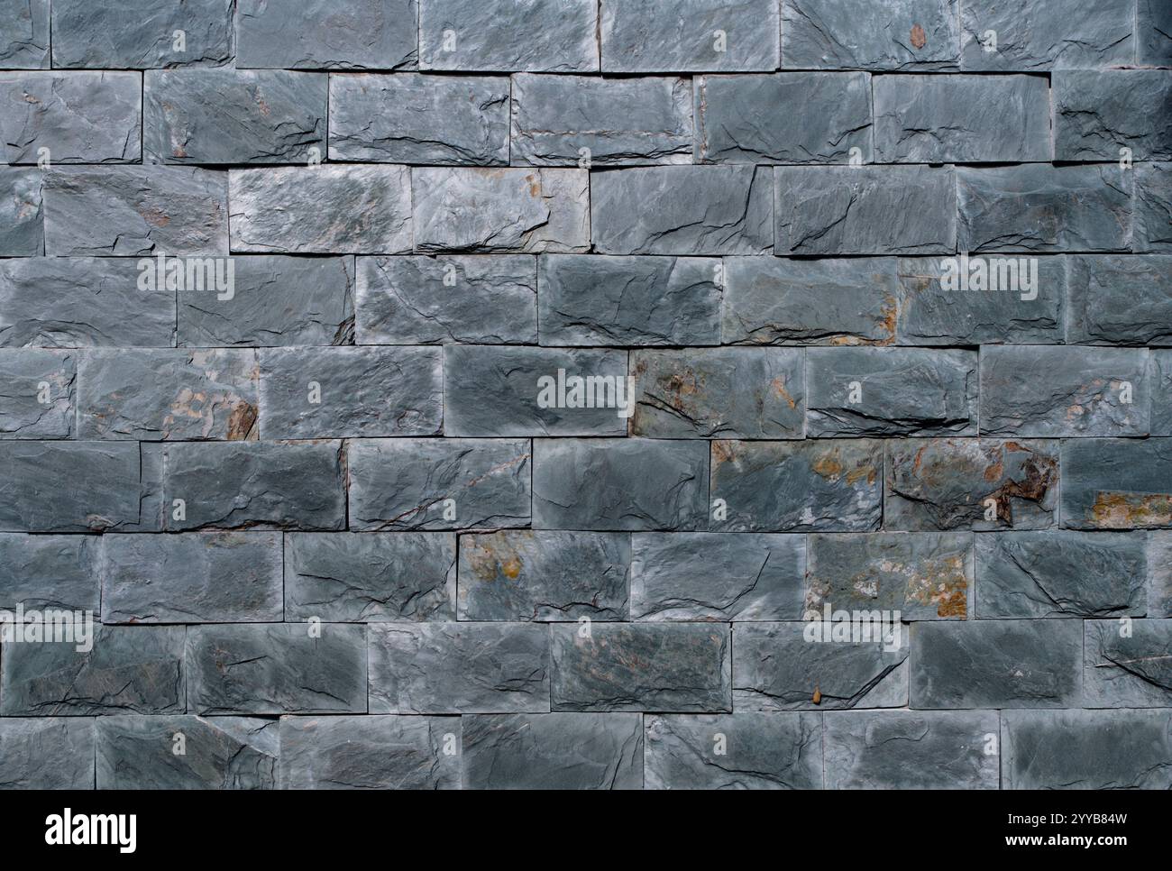 Un muro di mattoni di colore grigio. Il muro è fatto di mattoni. I mattoni sono di dimensioni diverse Foto Stock