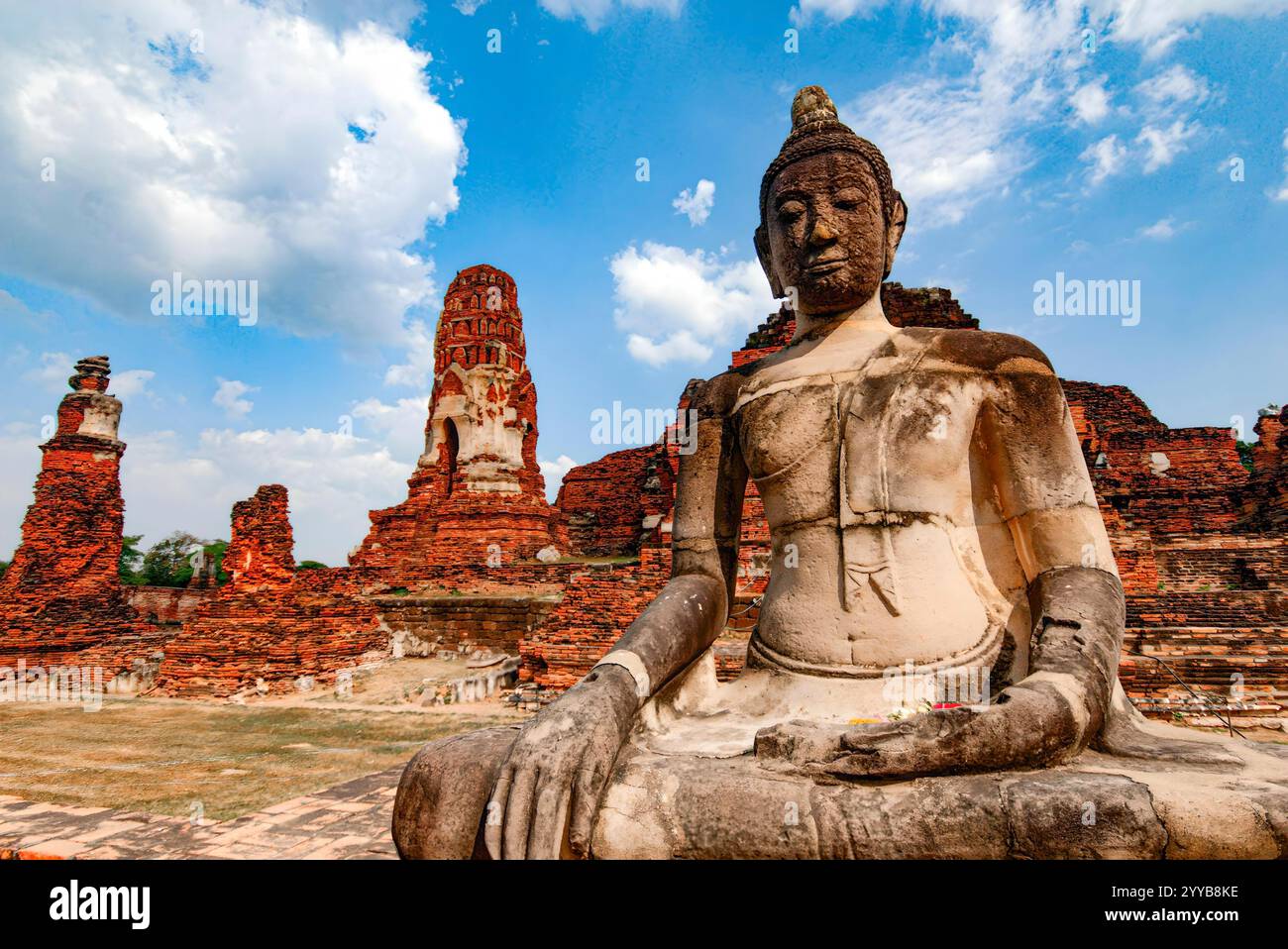 Di fronte ad un grande edificio si trova una statua di Buddha. La statua è bianca e ha una veste marrone Foto Stock