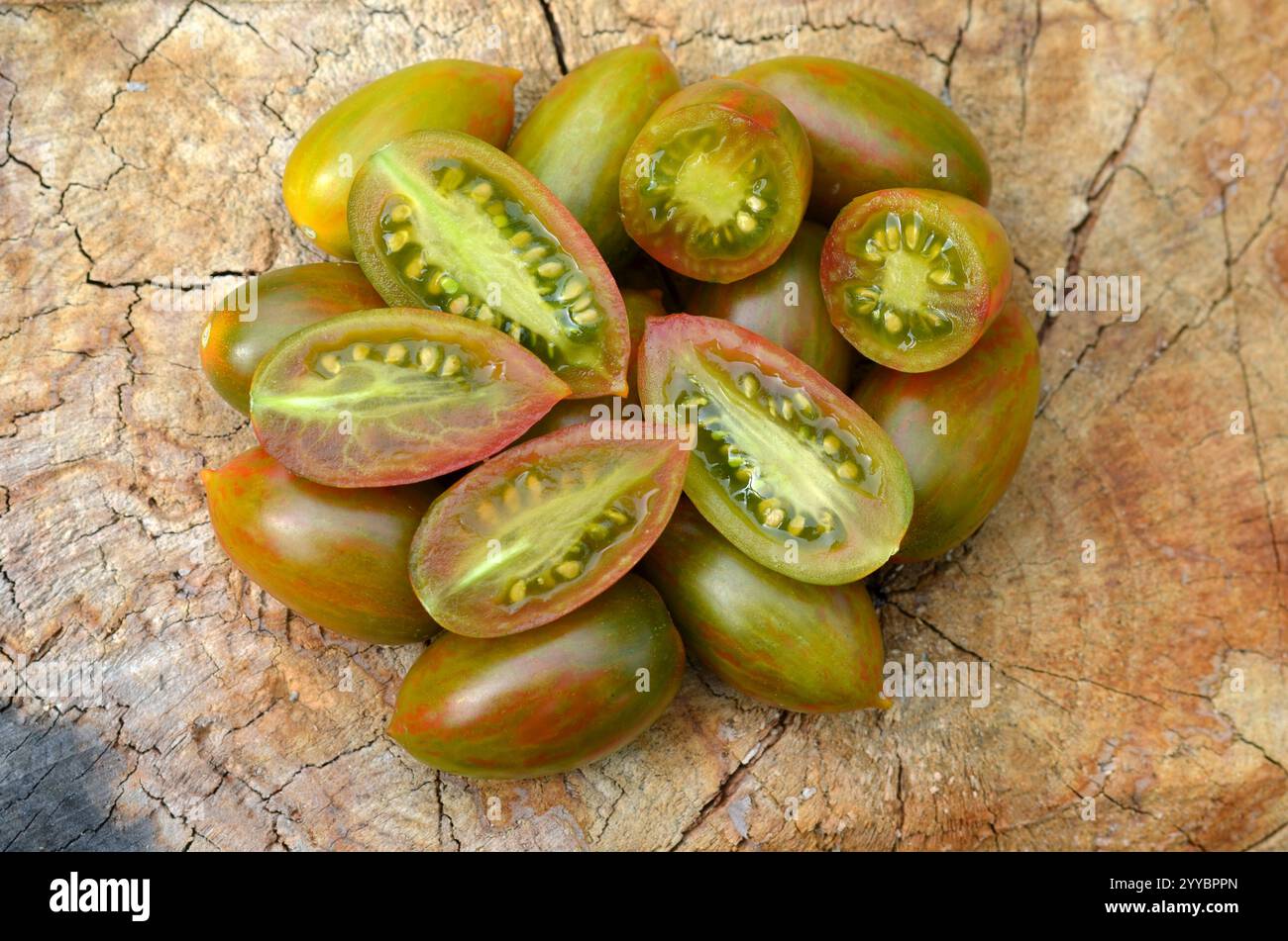 I pomodori a strisce verdi maturi, appartenenti alla categoria dei pomodori dell'uva, sono presentati in forma intera, nonché in una sezione longitudinale e trasversale. Foto Stock