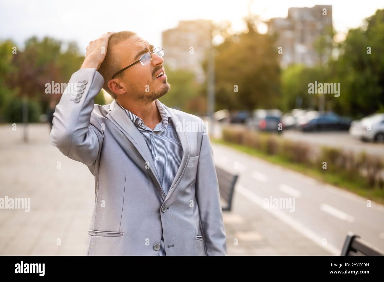 Ritratto di un giovane uomo d'affari deluso che sta in piedi per strada e sta pensando. Uomo d'affari ansioso e premuroso dopo il lavoro. Foto Stock