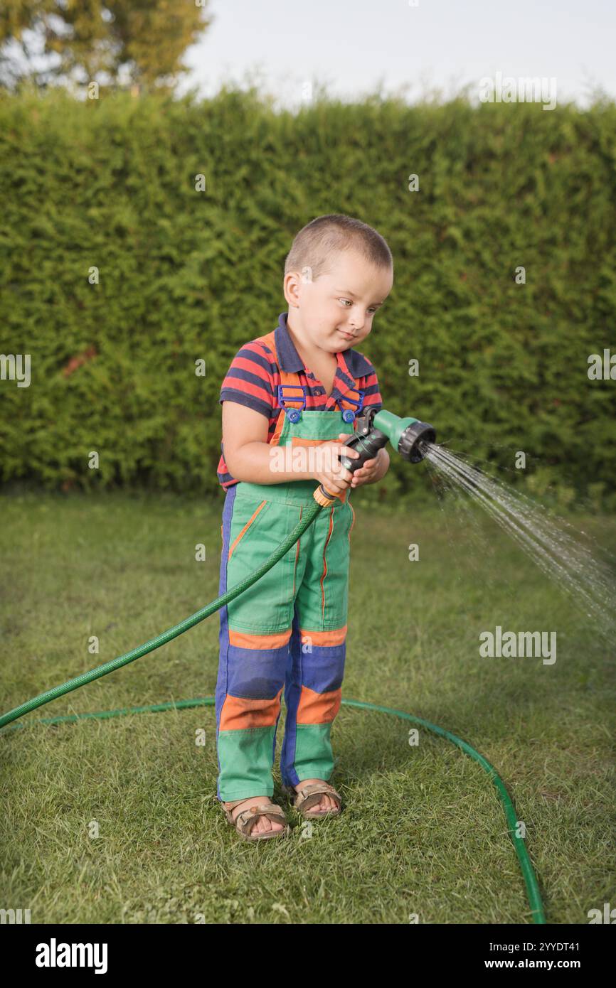 Bambino che gioca con il potere e gli attrezzi da giardino sul prato Foto Stock