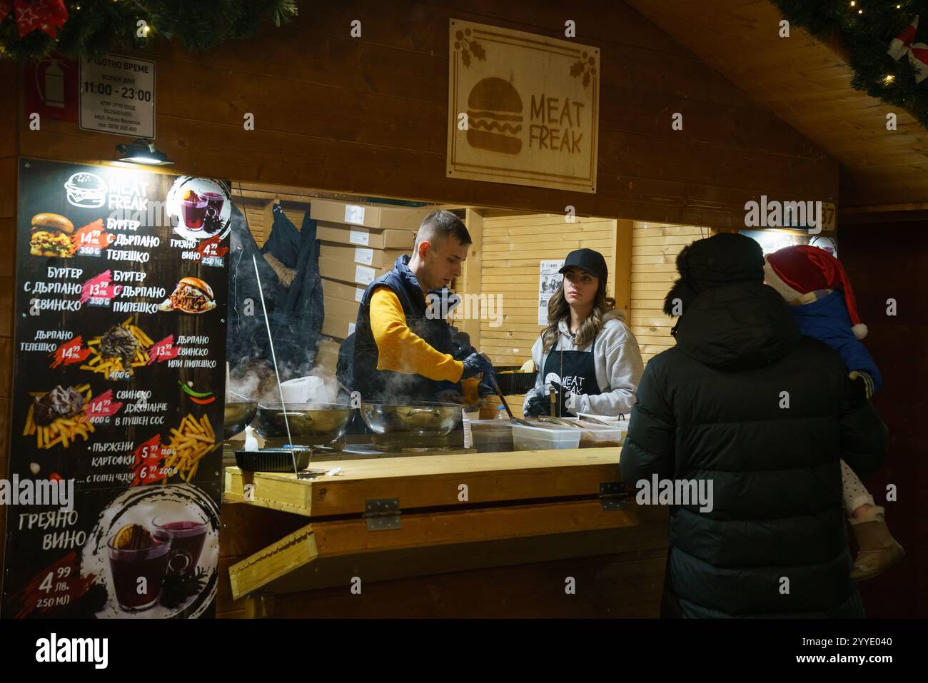 Un'accogliente bancarella di mercatini di Natale a NDK, Sofia, Bulgaria. Il chiosco "Meat Freak" offre prelibatezze natalizie, tra cui hamburger, VIN brulé e patatine fritte. Foto Stock