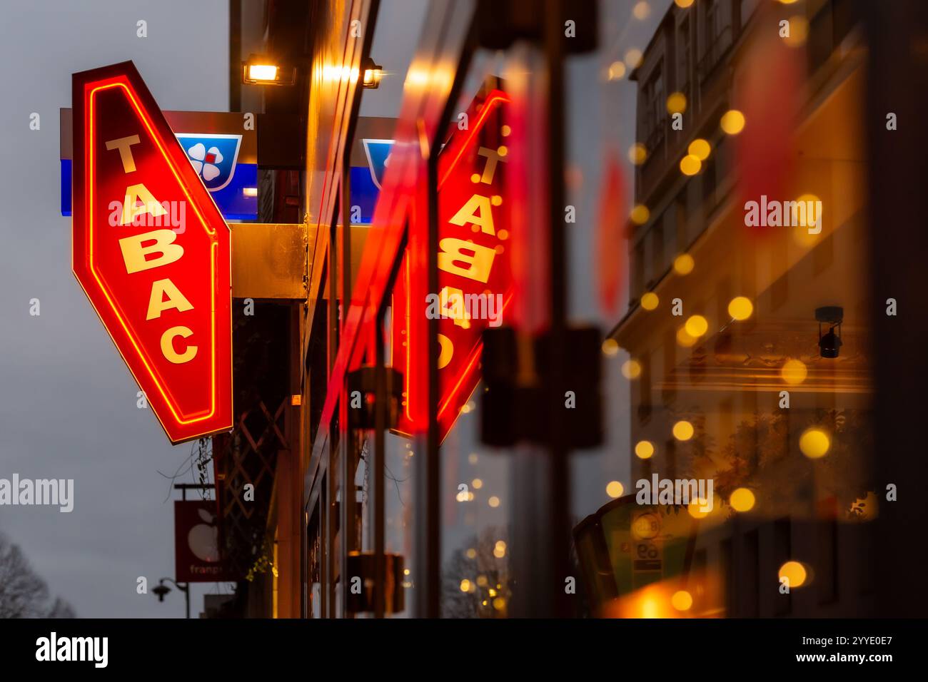 Il famoso simbolo Tabac che si trova in tutta Parigi e Francia. Un'immagine forte del logo Tabac riflessa nella vetrina del negozio. Foto Stock