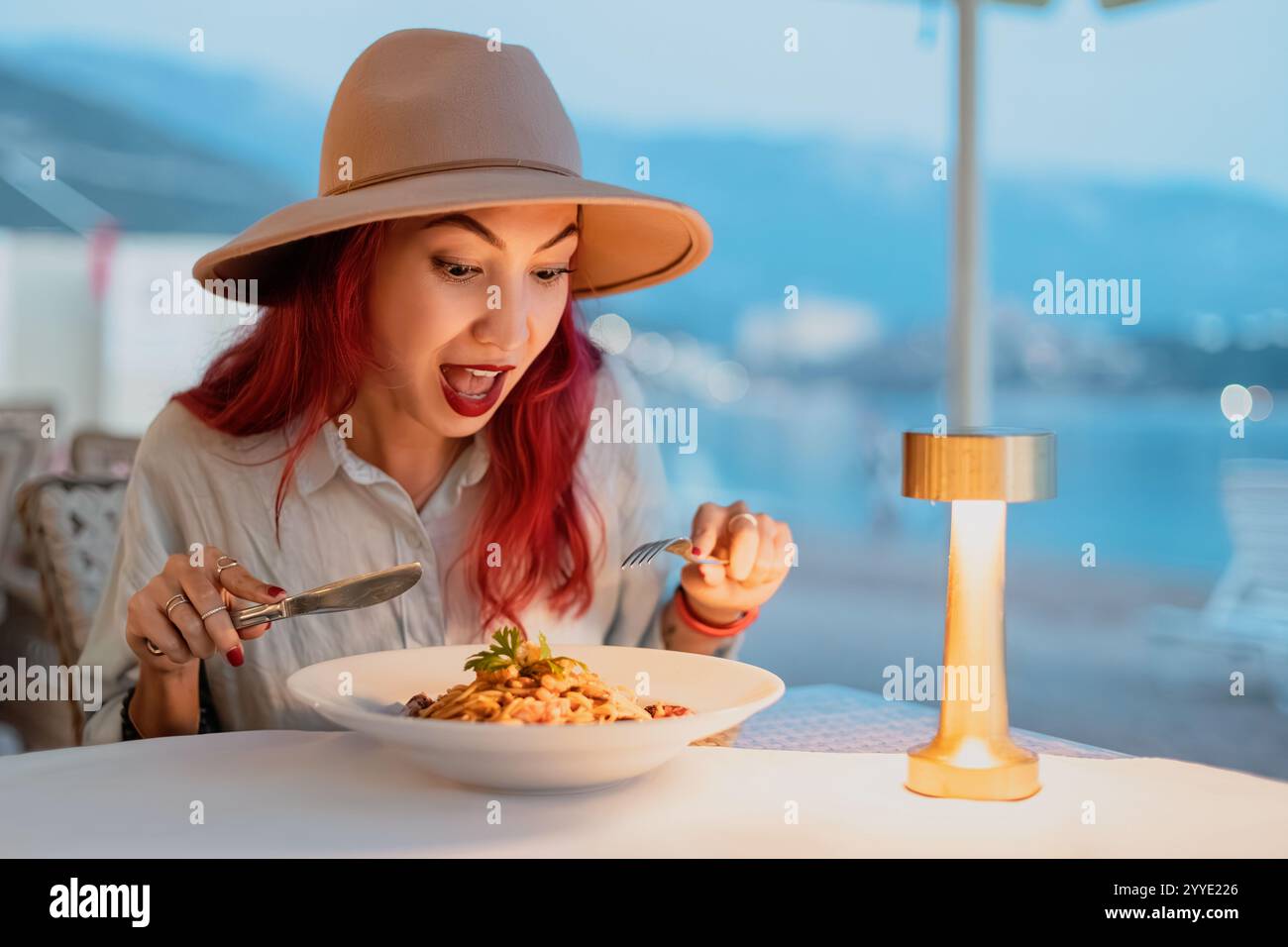 Felice turista che mangia deliziosi piatti di pasta a base di pesce in un elegante ristorante italiano sul mare Foto Stock