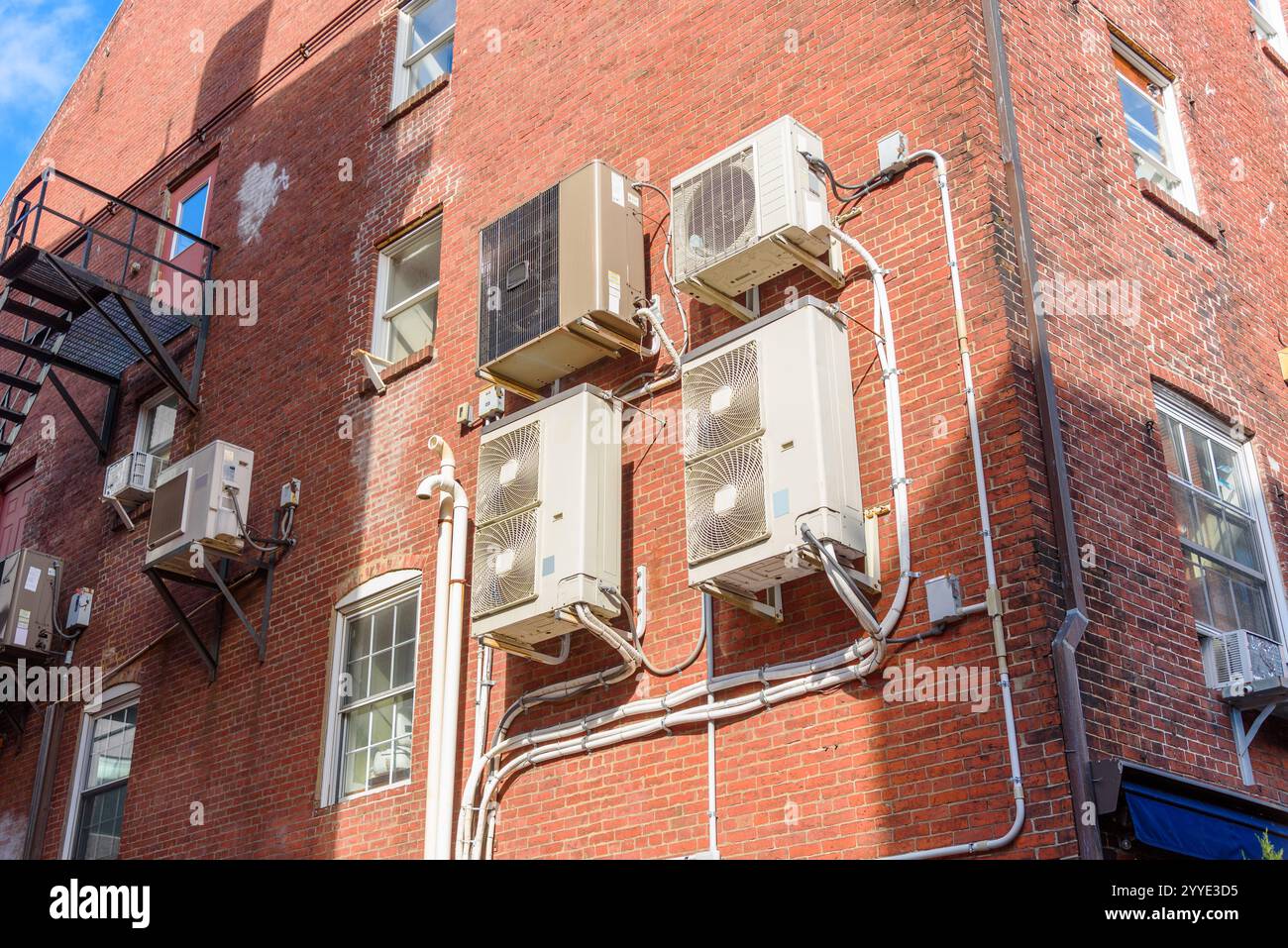 Unità del sistema HVAC sulla parete esterna di un vecchio edificio in mattoni in una giornata di sole Foto Stock