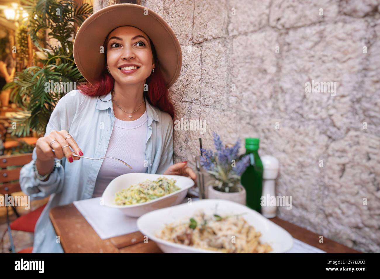 Giovane donna che mangia pasta in un tipico ristorante italiano, assaporando la cucina locale durante il suo viaggio Foto Stock
