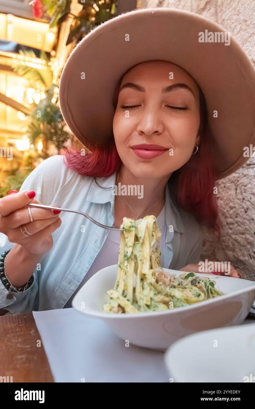 Il turista assaggia la deliziosa pasta al ristorante, gustando i sapori autentici dell'Italia Foto Stock
