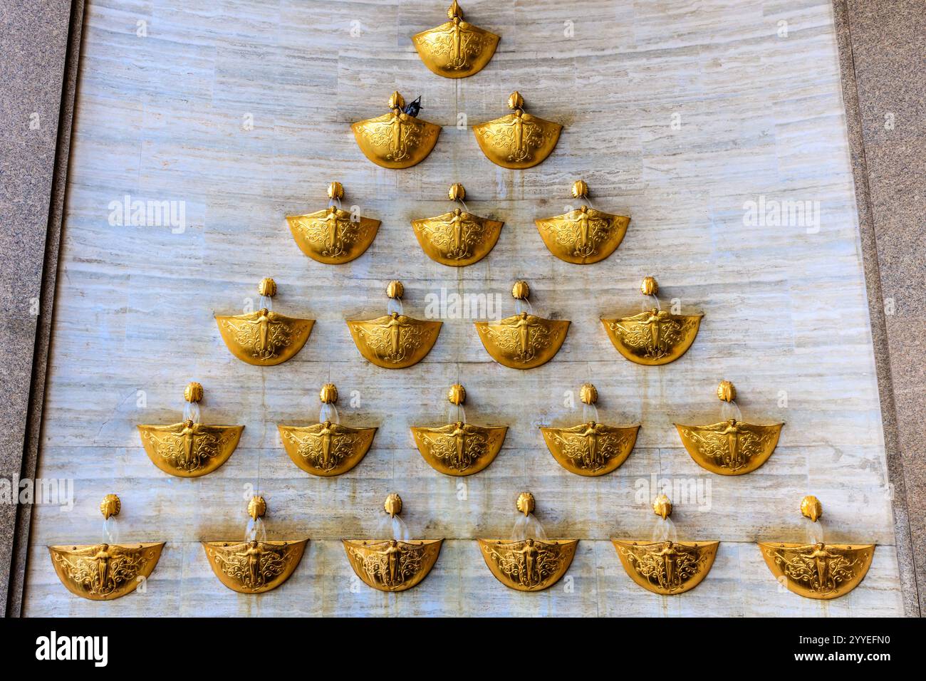 Un muro con piastrelle dorate e bianche e ciotole dorate e bianche. Le ciotole sono disposte a forma di triangolo Foto Stock