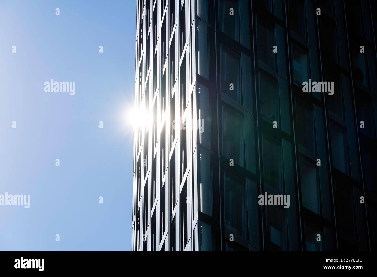 La luce del sole si riflette sul moderno grattacielo in vetro con luce soffusa Foto Stock