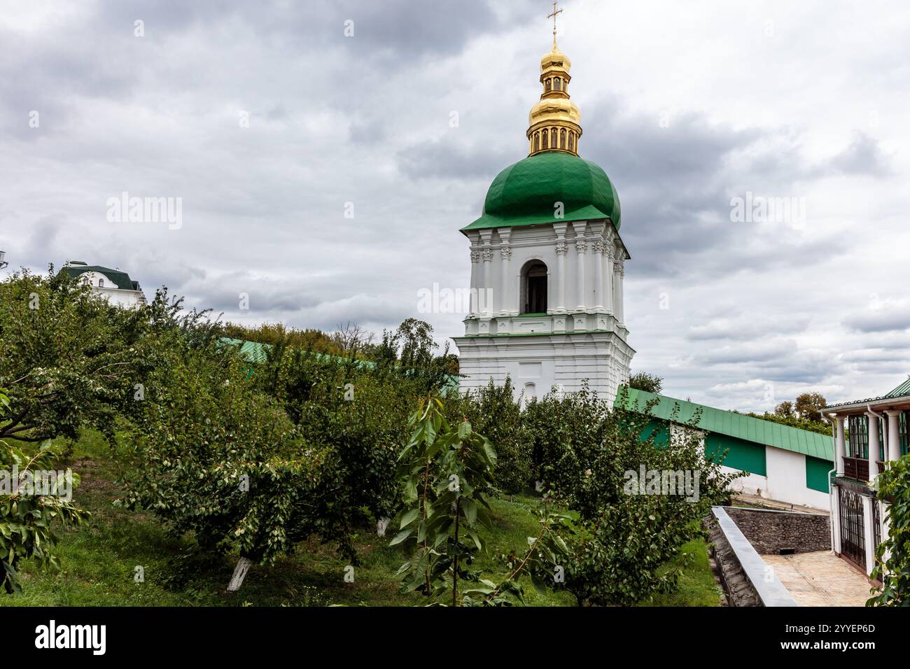 Un edificio verde e bianco con una cupola d'oro si trova su una collina. L'edificio è circondato da alberi ed è una chiesa. Il cielo è nuvoloso e nel complesso Foto Stock