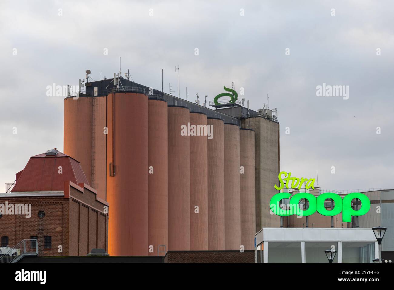 Falkenberg, Svezia - 6 ottobre 2024: Cartello Coop, silos in calcestruzzo e costruzione di fabbrica. Nessuna persona visibile Foto Stock