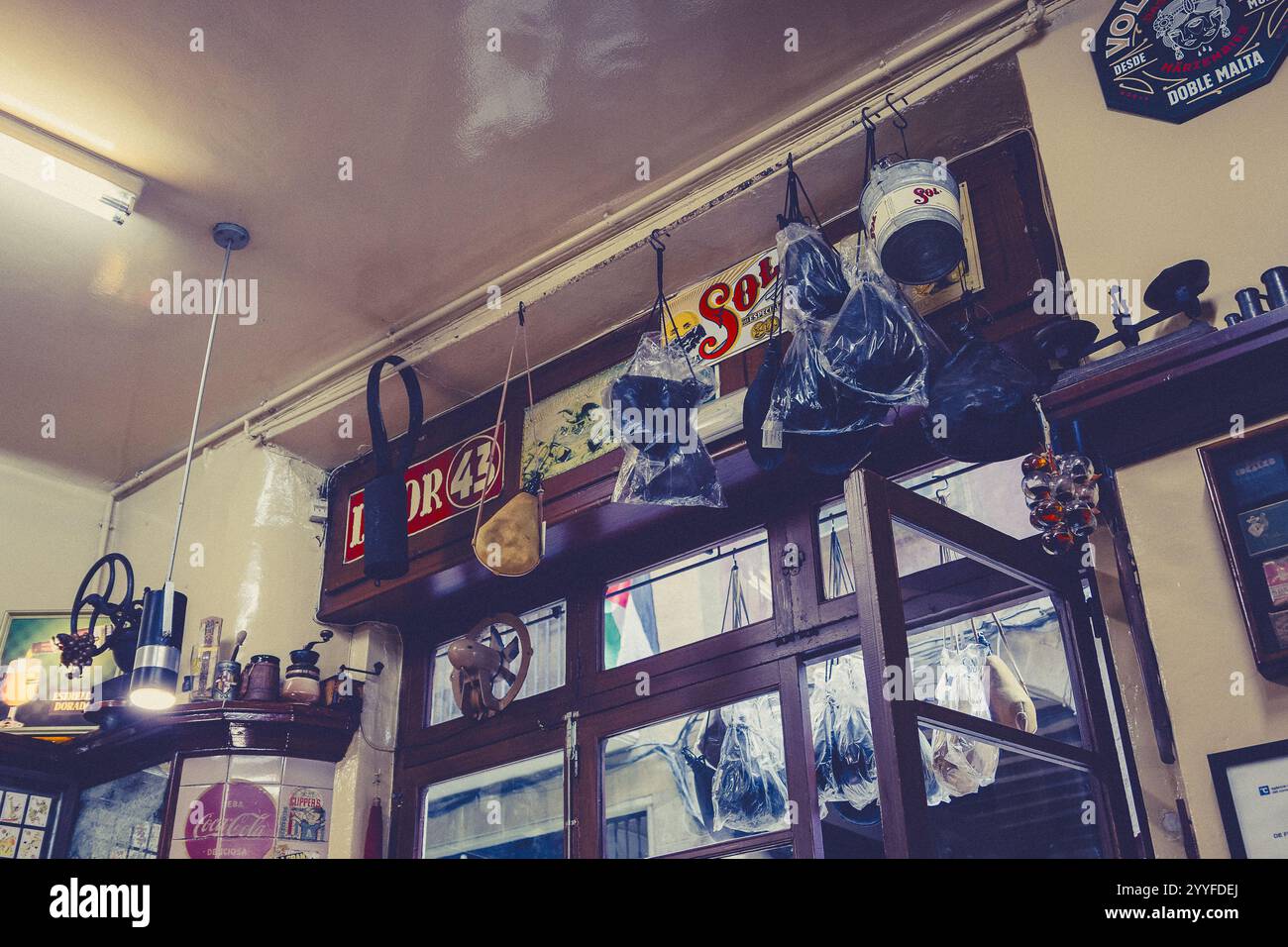 Interni vintage con arredi eclettici, tra cui cartelli retrò, strumenti e oggetti appesi, che catturano il fascino di un locale rustico Foto Stock