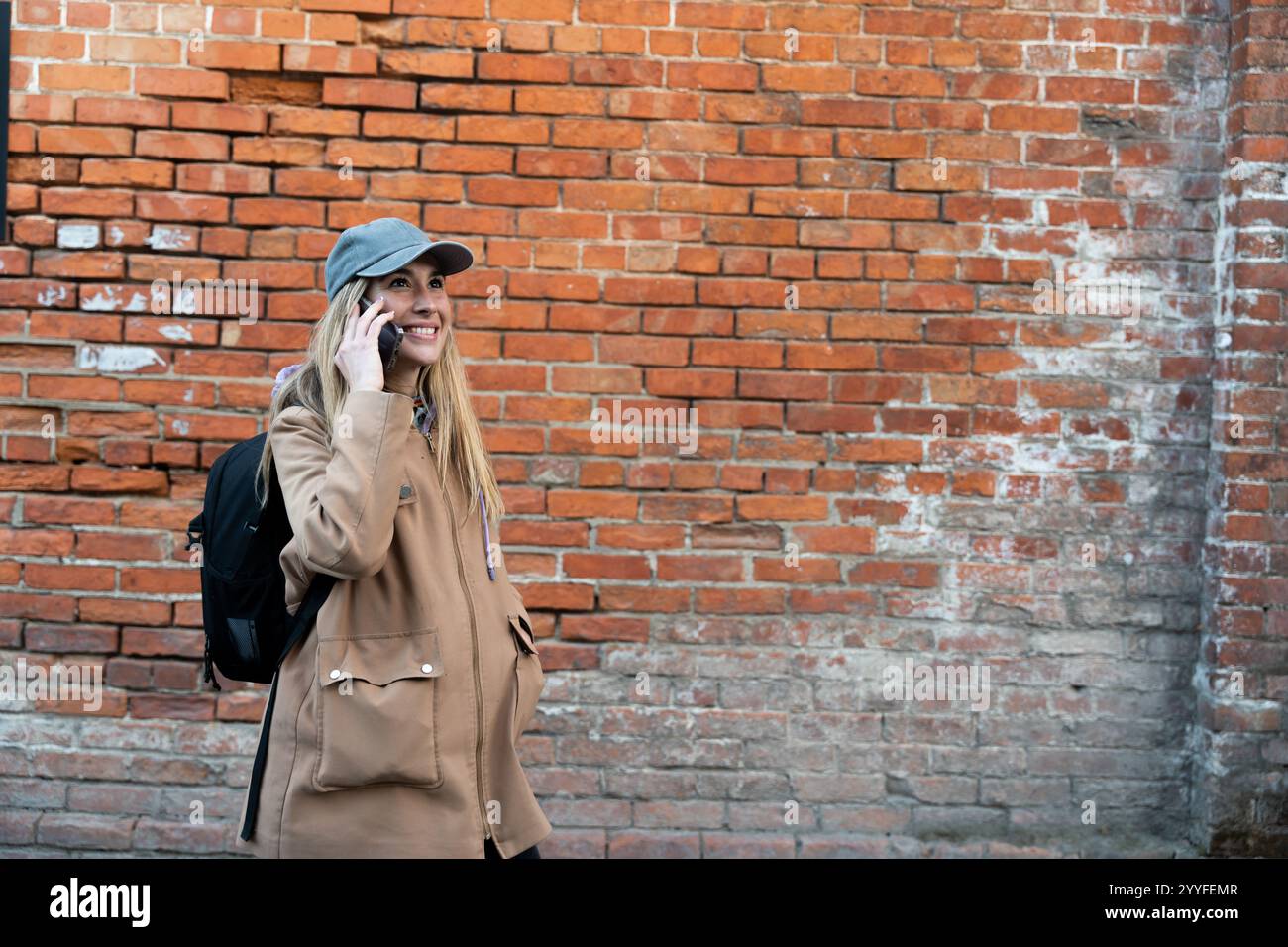 Donna occasionale che parla al telefono per strada. Sfondo murario Foto Stock