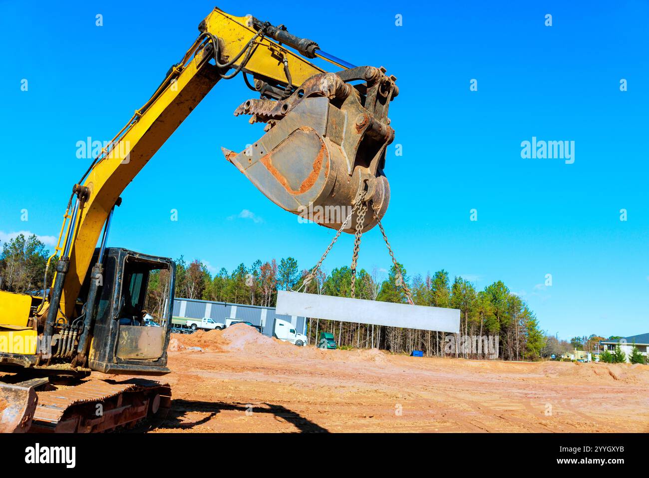 Gli operai edili utilizzano gru per sollevare grandi travi in acciaio nel cantiere durante l'area di lavoro Foto Stock