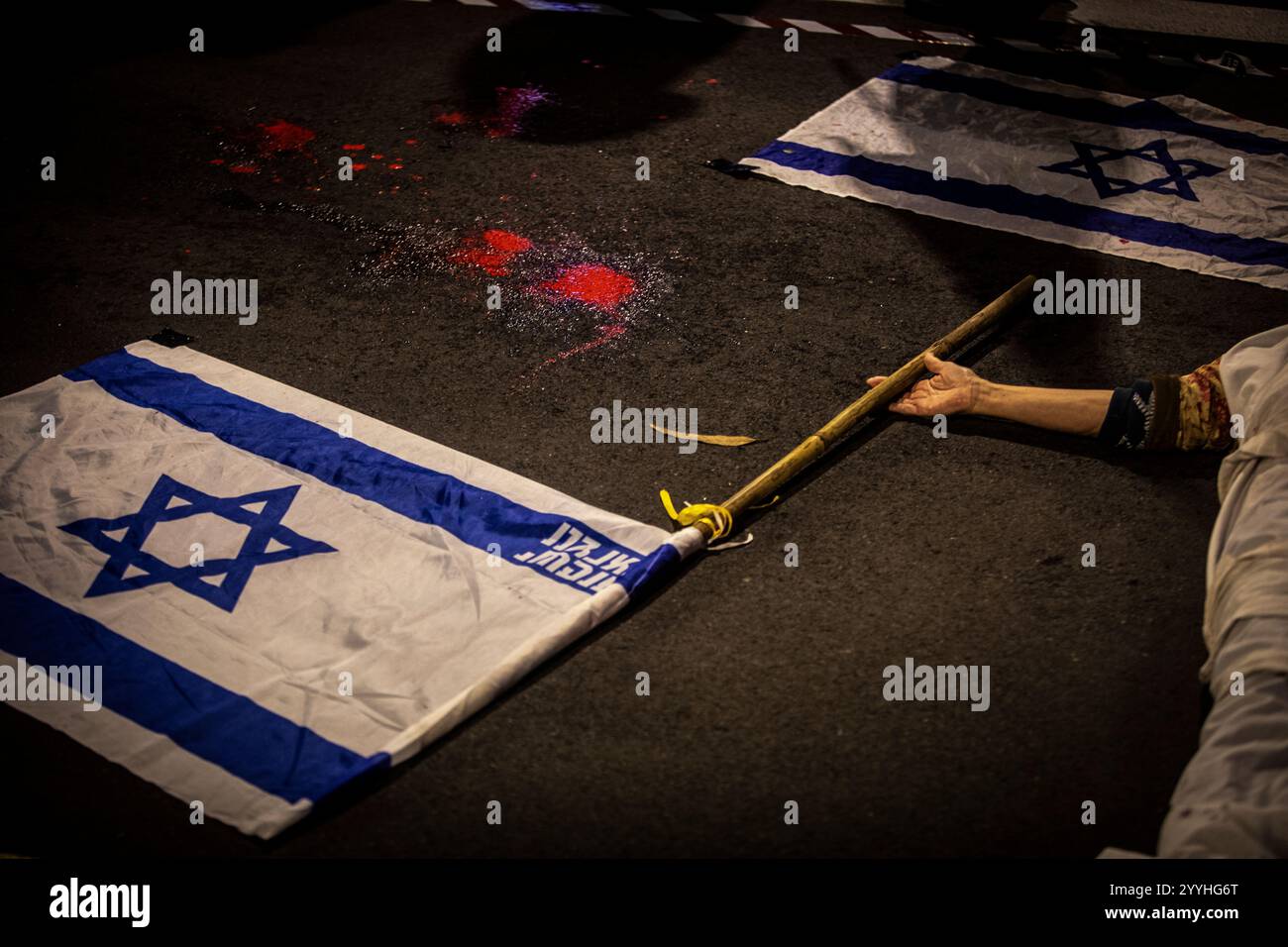 Un manifestante detiene una bandiera israeliana durante una protesta a Tel Aviv sabato 21 dicembre 2024. Sabato, migliaia di persone sono scese per le strade di Israele chiedendo all'attuale governo guidato dal primo ministro Benjamin Netanyahu di raggiungere un accordo con Hamas. Foto di Eyal Warshavsky. Foto Stock