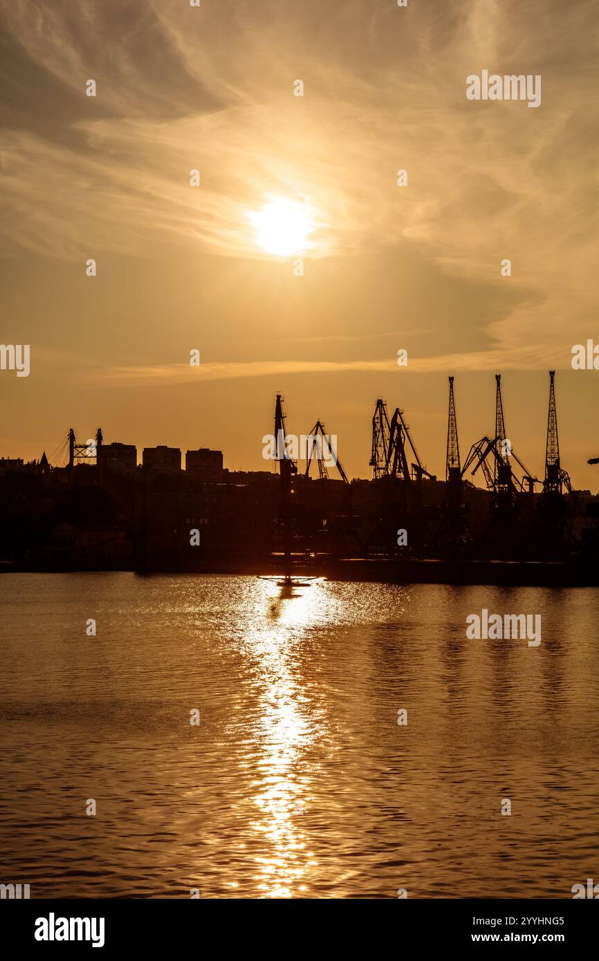 Il sole sta tramontando sull'acqua, proiettando un caldo bagliore sugli edifici sullo sfondo. La scena è tranquilla e serena, con l'acqua che riflette Foto Stock
