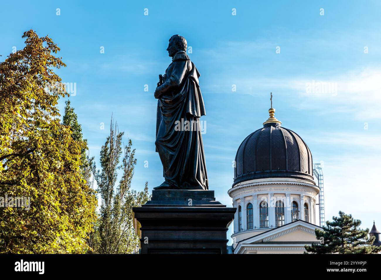 Una statua di una donna si trova di fronte a un grande edificio. La statua è circondata da alberi e il cielo è limpido e blu. Concetto di pace e tranqui Foto Stock