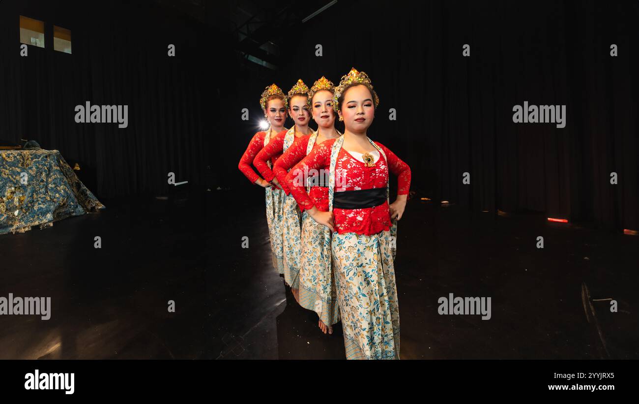 Un gruppo di ballerini giavanesi che indossano costumi rossi uniformi crea un'armonia visiva che stupisce il pubblico di notte Foto Stock
