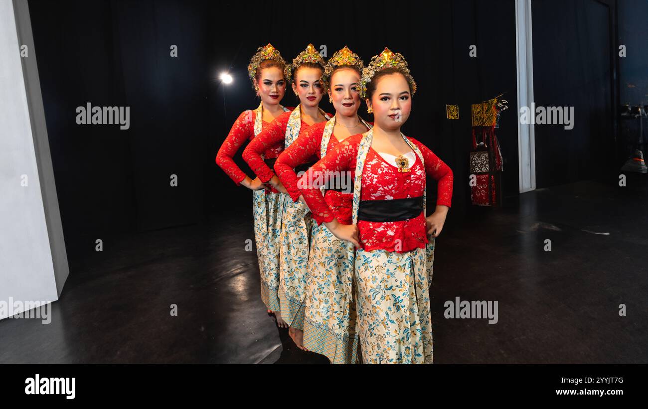 Un gruppo di ballerini giavanesi che indossano costumi rossi uniformi crea un'armonia visiva che stupisce il pubblico di notte Foto Stock