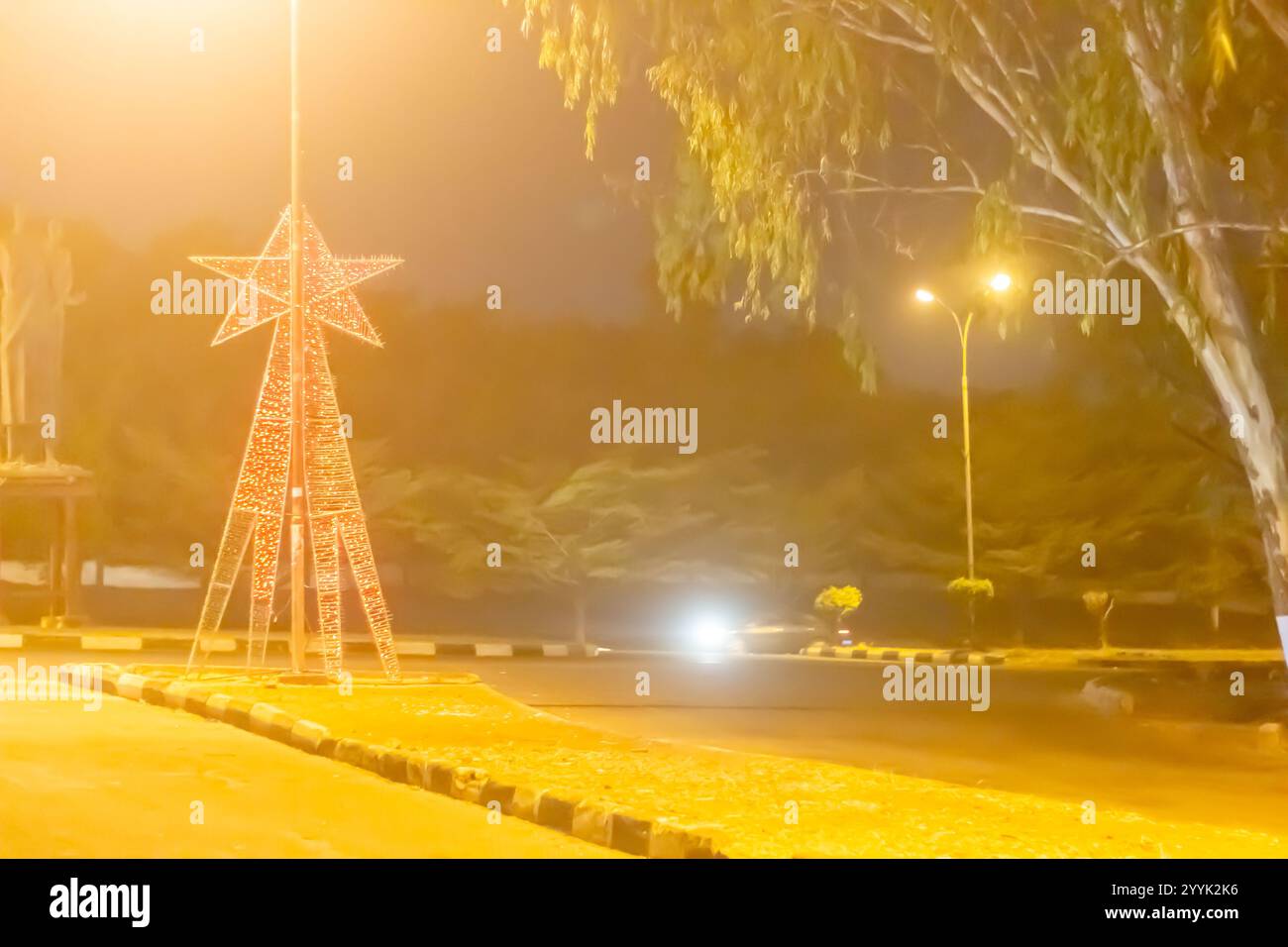 Luci delle stelle festive su una rotonda urbana di notte Foto Stock