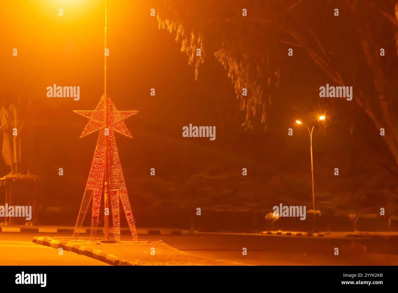 Luci delle stelle festive su una rotonda urbana di notte Foto Stock