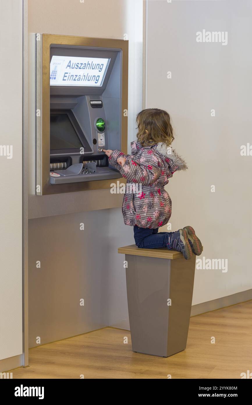 Bambino di fronte al bancomat Foto Stock