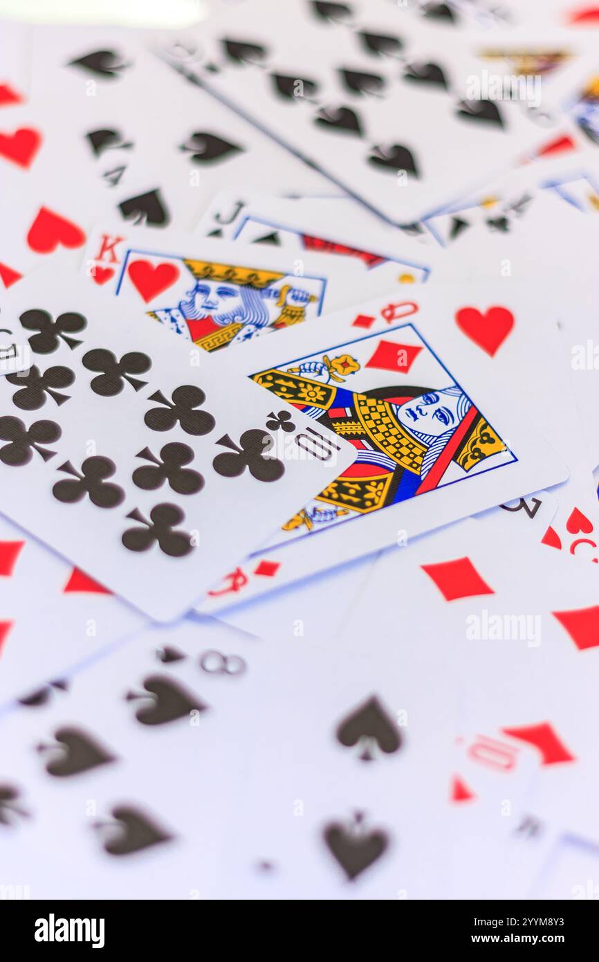 Un mazzo di carte da gioco con il Re dei cuori in cima. Le carte sono sparse su una superficie bianca Foto Stock