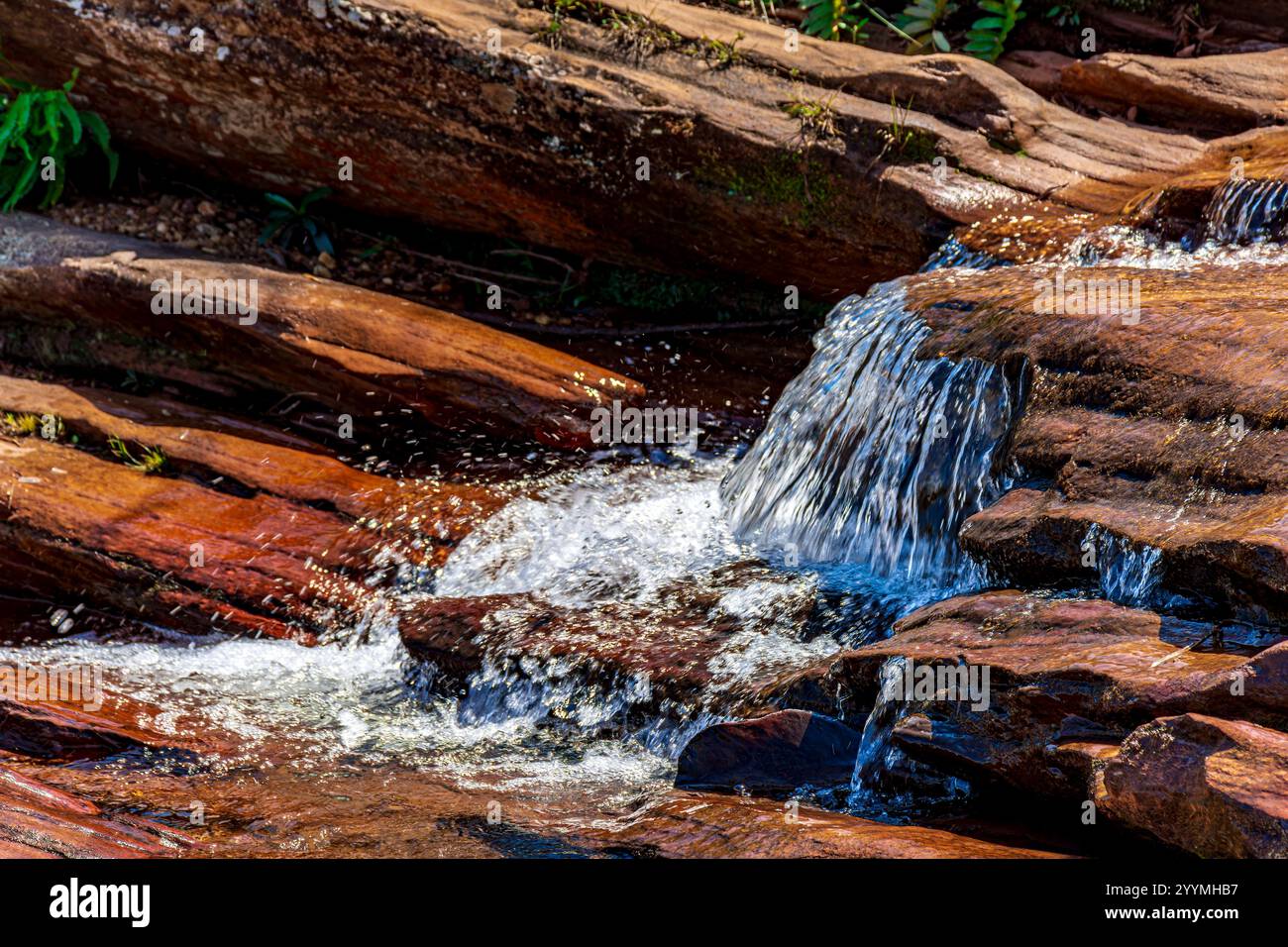 L'acqua scorre sopra le rocce formando una piccola cascata Foto Stock