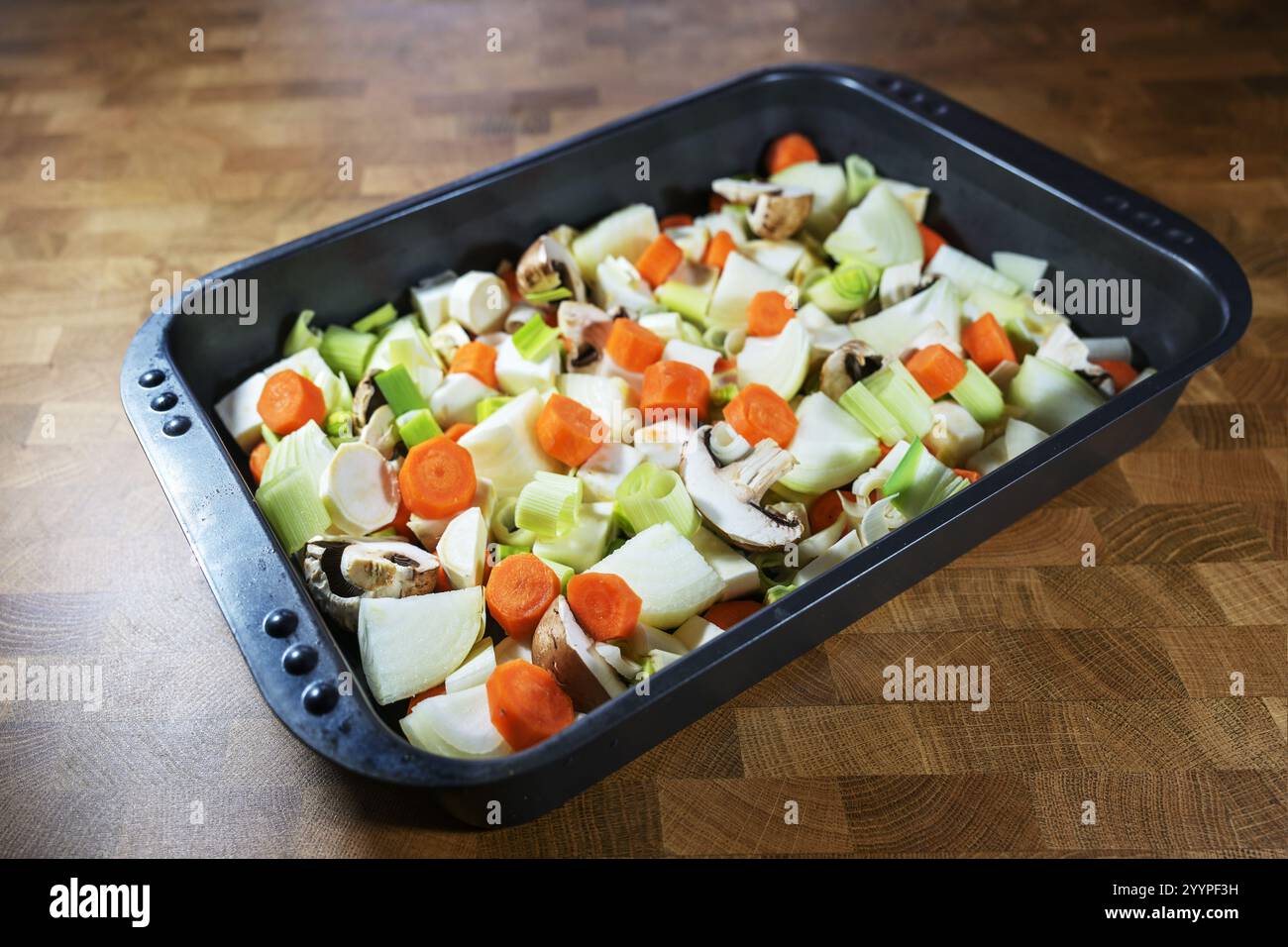 Mirepoix di cottura, miscuglio di verdure crude a dadini come carote, cipolle, sedano, porri e funghi in un piatto da forno, parte della cucina francese, fl Foto Stock