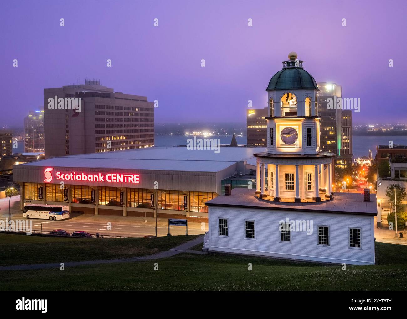 L'orologio della città vecchia di Halifax si illumina di calore contro il crepuscolo, con lo Scotiabank Centre e le luci del porto che aggiungono un contrasto moderno a questa vista iconica Foto Stock