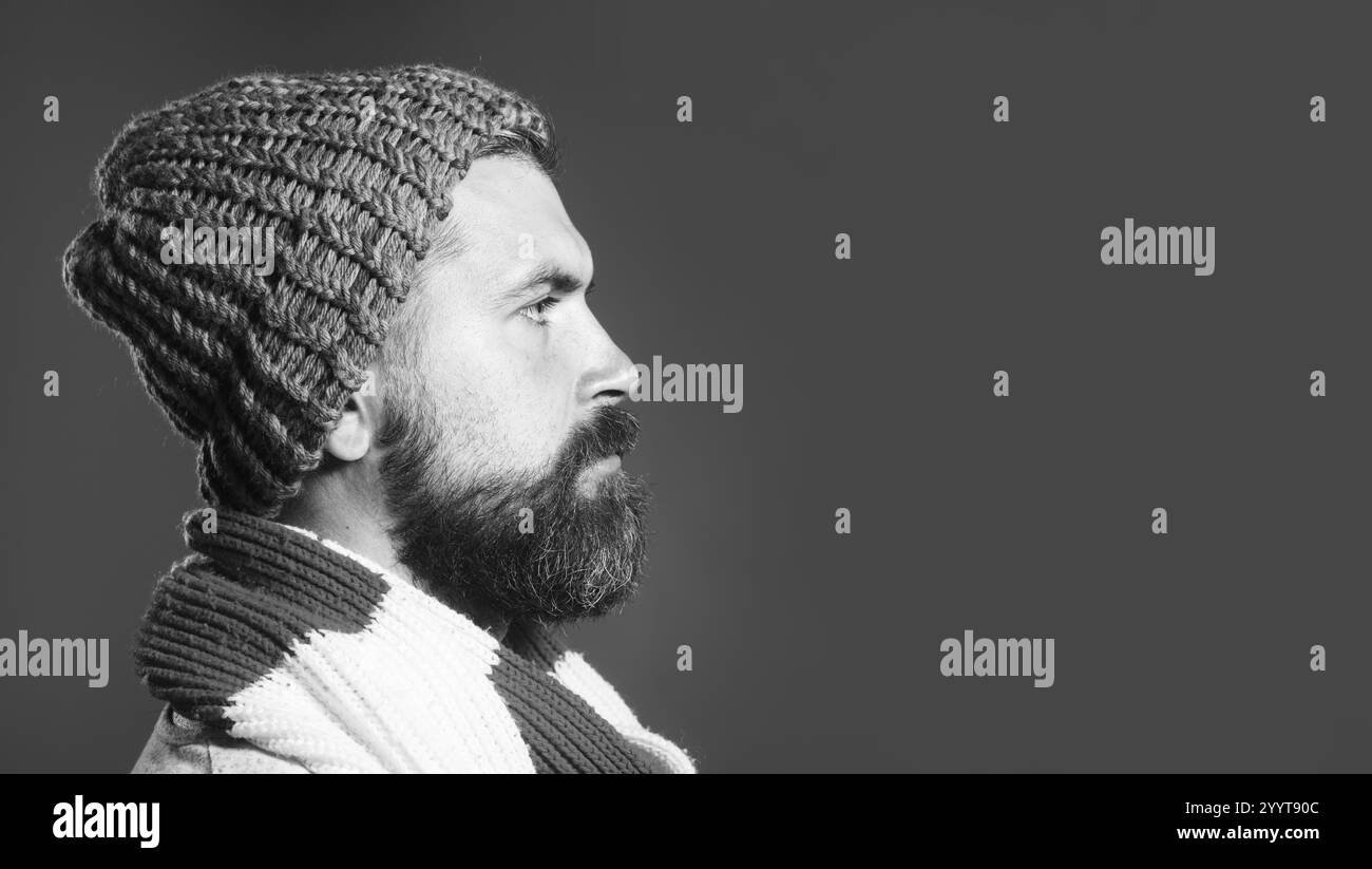 Uomo barbuto alla moda con cappello e sciarpa di lana. Bell'elegante ragazzo con barba e baffi che guarda uno spazio vuoto per la pubblicità. il wi degli uomini Foto Stock