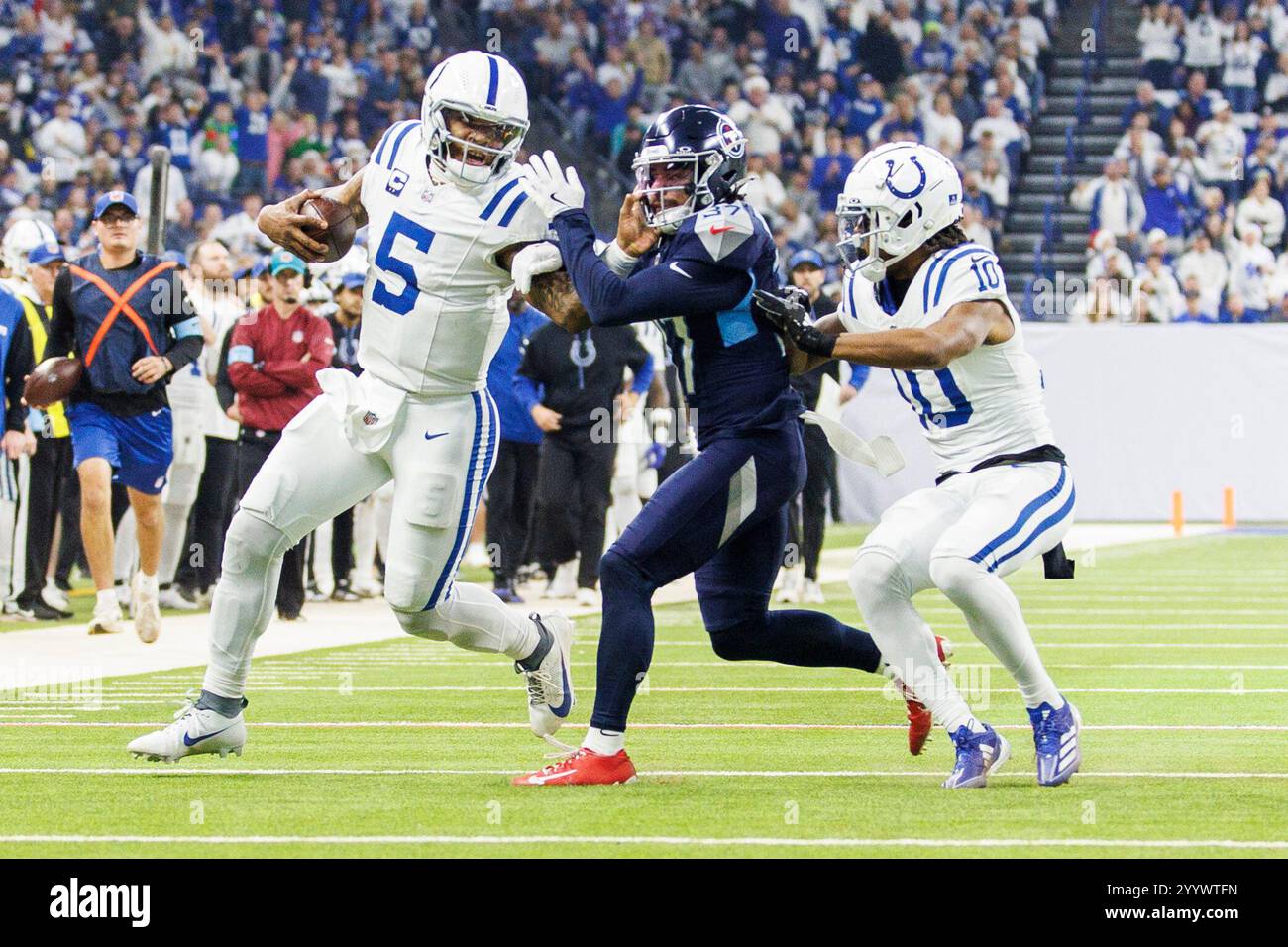 Indianapolis, Indiana, Stati Uniti. 22 dicembre 2024. Il quarterback degli Indianapolis Colts Anthony Richardson (5) corre con la palla e le braccia rigide della safety dei Tennessee Titans Amani Hooker (37) durante la gara NFL al Lucas Oil Stadium di Indianapolis, Indiana. John Mersits/CSM/Alamy Live News Foto Stock