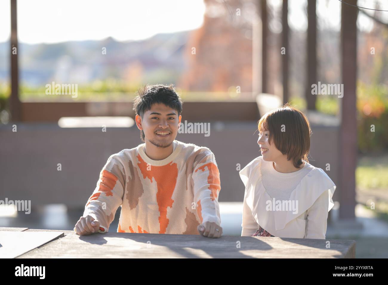 Una coppia di 20 anni è seduta su una panchina e chiacchiera in un grande parco con la natura a Handa City, nella prefettura di Aichi. Foto Stock