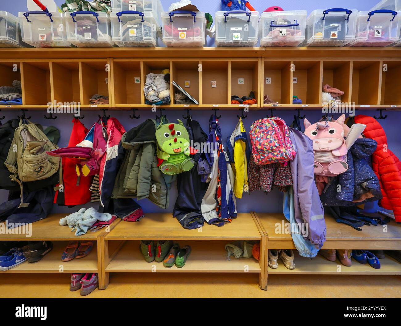 Germania - immagine simbolica KITA. Cappotti, giacche e zaini di unicorno di bambini appesi a un guardaroba in un asilo. Foto Stock