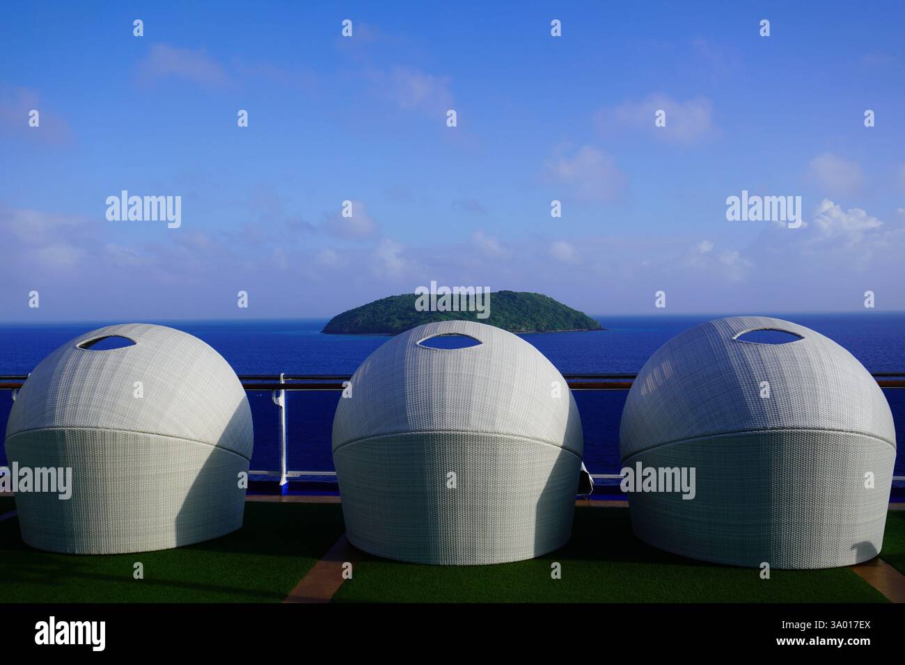 Sedie a sdraio con cappuccio di fronte ad una piccola isola tropicale Foto Stock