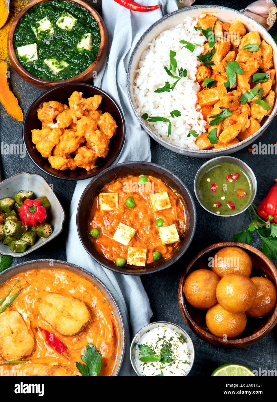 Piatti della cucina indiana. Curry, pollo al burro, riso, lenticchie, paneer, samosa, spezie. Ciotole e piatti con cibo indiano. Vista dall'alto. Foto Stock