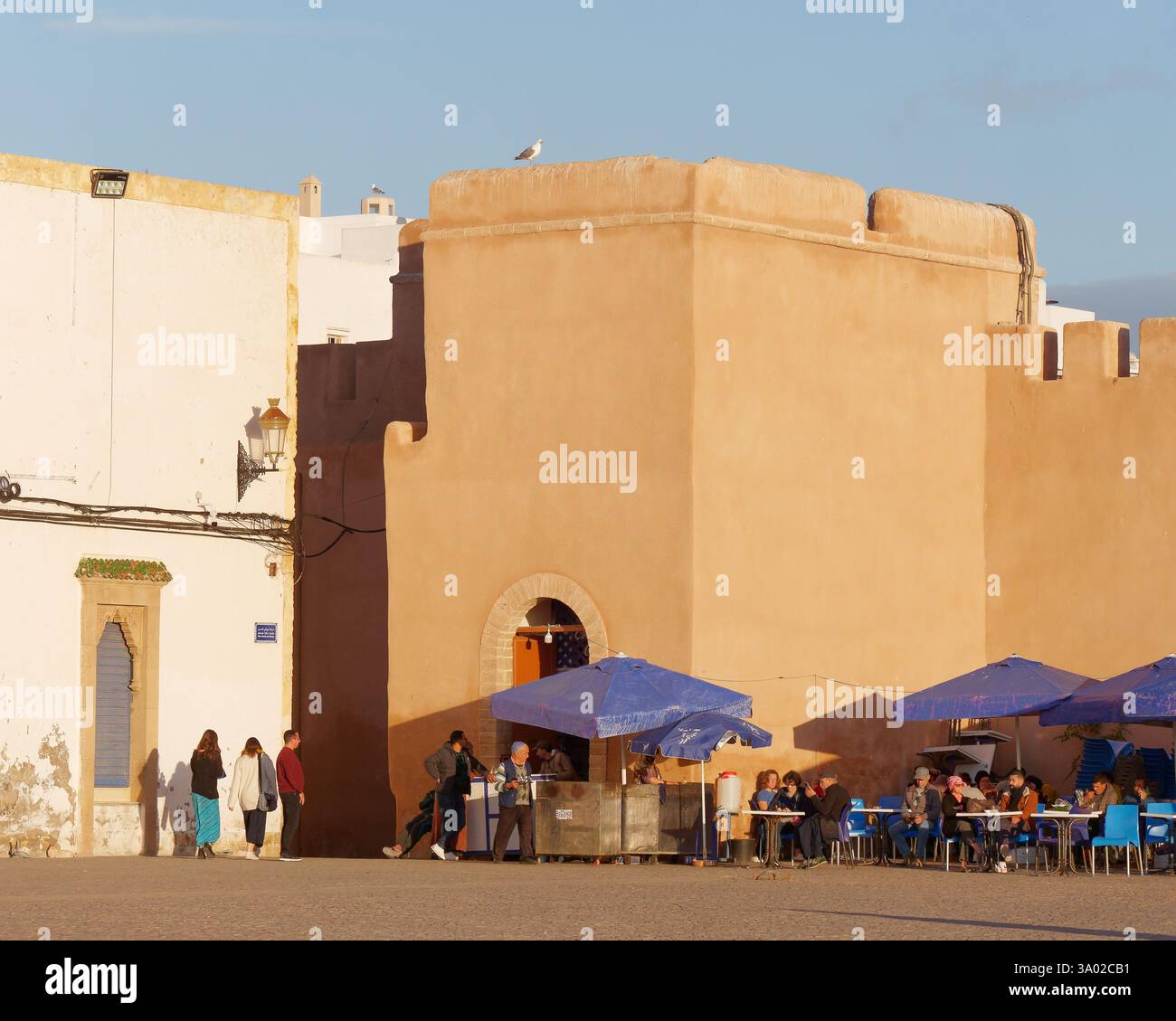 Persone in un piccolo caffè/ristorante la sera sotto le mura della storica Medina di Essaouria, in Marocco. Febbraio/marzo 2025 Foto Stock
