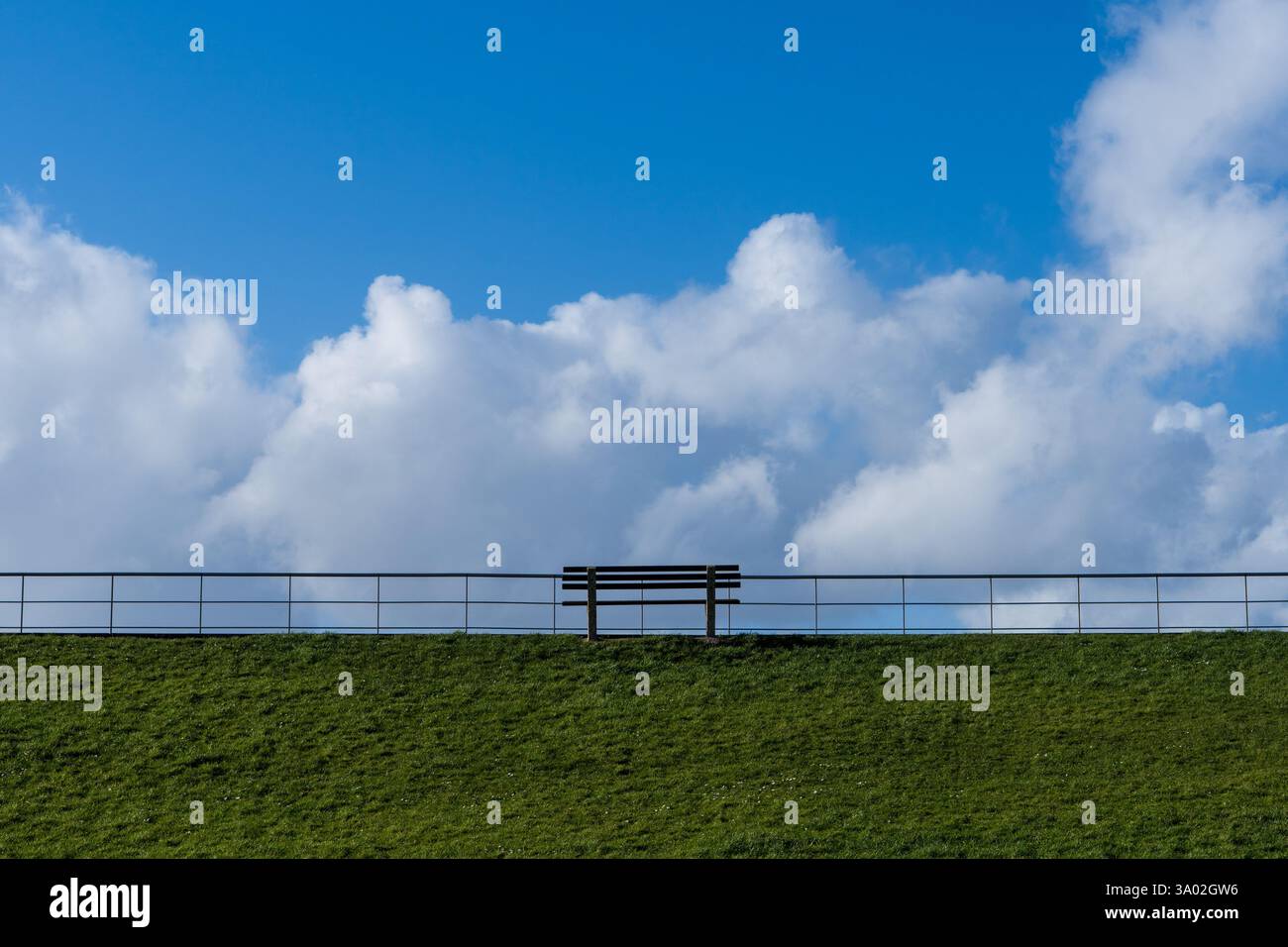 Una panchina su un sentiero con cielo blu ed erba Foto Stock