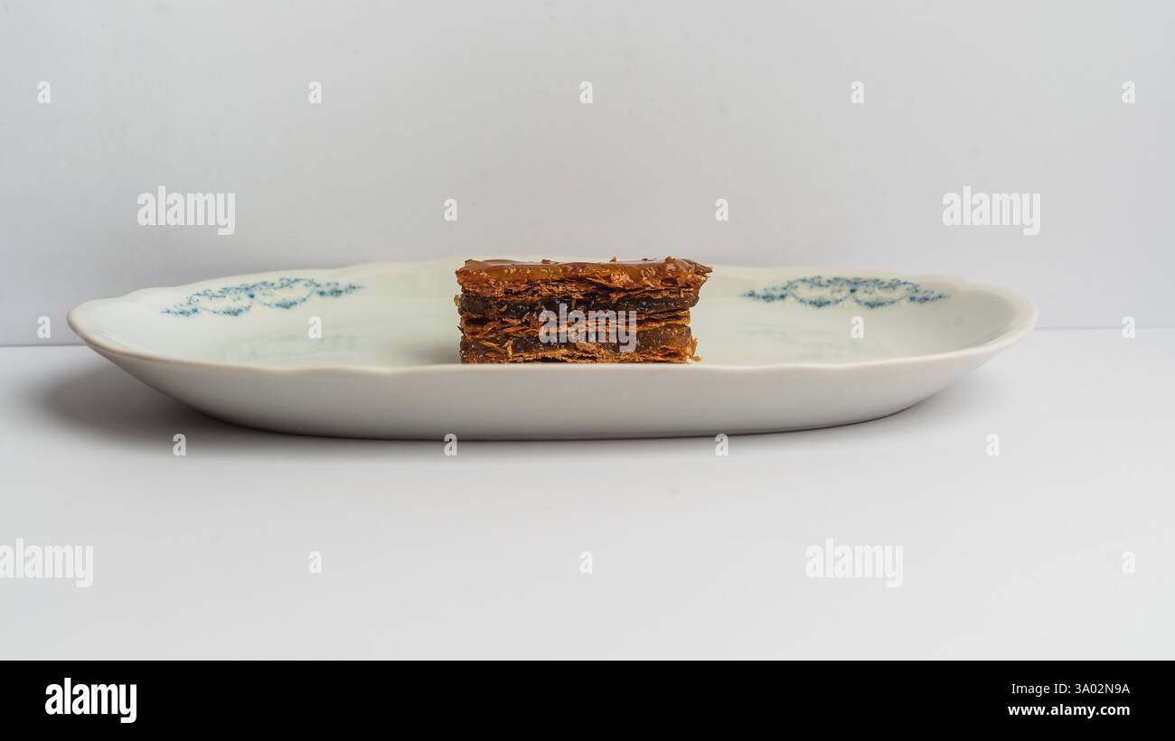 Un dessert a strati splendidamente presentato si trova su un piatto classico in porcellana, con strati intricati e una finitura lucida, perfetta per il lusso Foto Stock