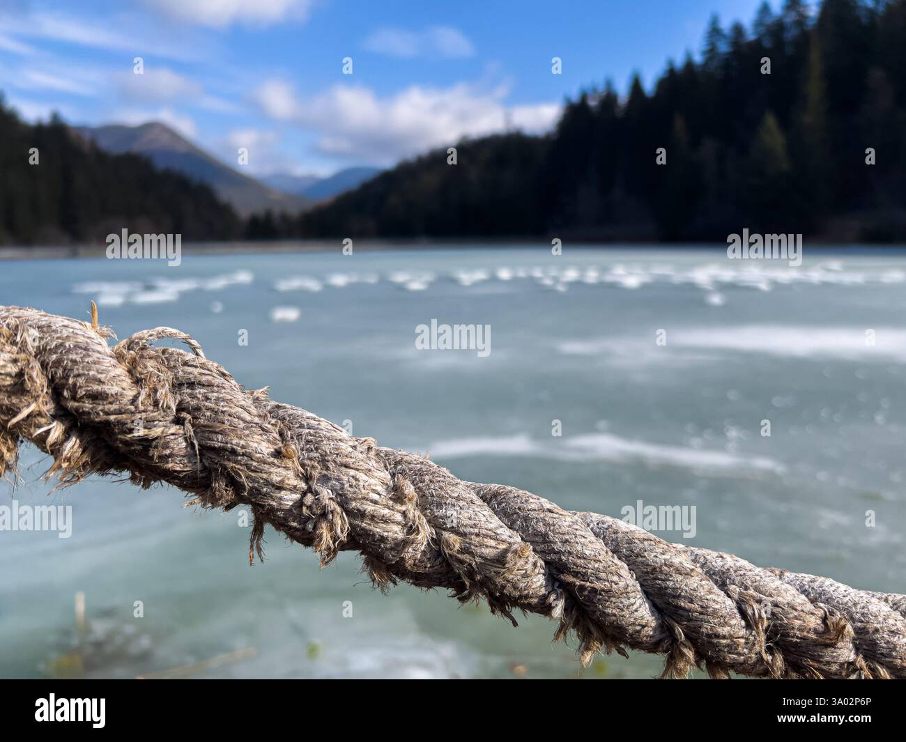 Primo piano di una corda con un lago ghiacciato e alberi sullo sfondo Foto Stock