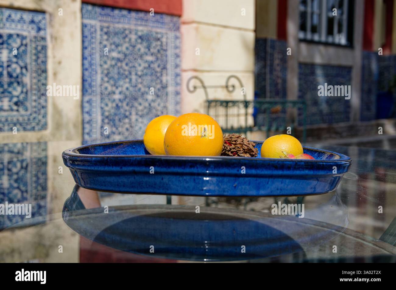 Un vassoio di ceramica blu vibrante con agrumi poggia su un tavolo di vetro, adagiato sulle piastrelle azulejo di Fronteira Foto Stock