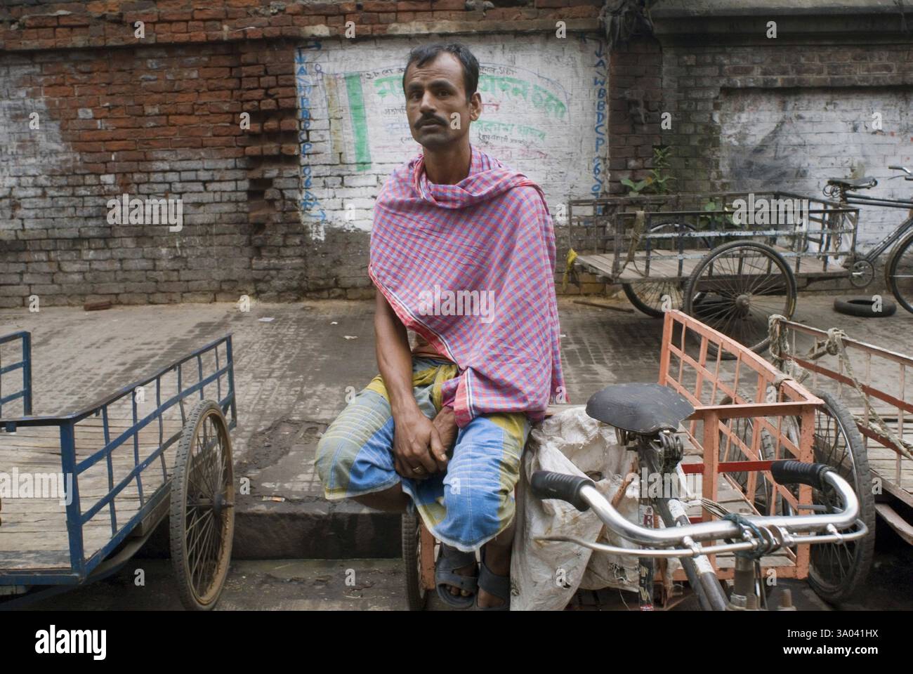 Pedala Rickshaw Rider in strada in attesa di passeggeri, Kolkata, Bengala Occidentale, India, Asia Foto Stock