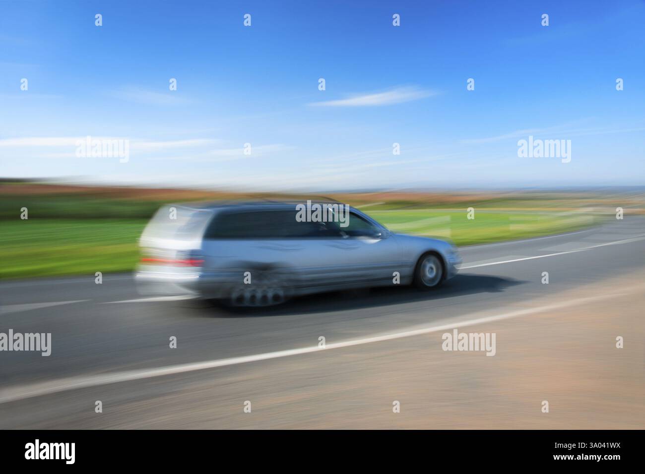 Silver station wagon che guida su strada di campagna sotto il cielo blu, motion blur, Turingia, Germania, Europa Foto Stock