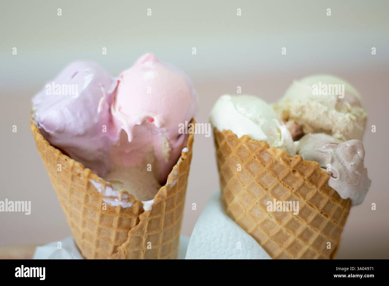 Un paio di gelati da latte che si fondono in coni per biscotti Foto Stock