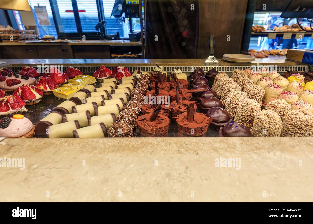 Splendida gamma di dessert gourmet assortiti in vetrina di panifici, con vari colori, texture e decorazioni Foto Stock