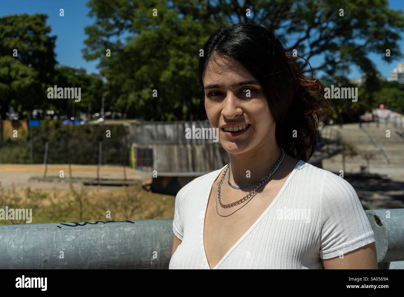 Ritratto di una giovane donna latina elegante sorridente in un parco cittadino, godendosi una giornata di sole Foto Stock